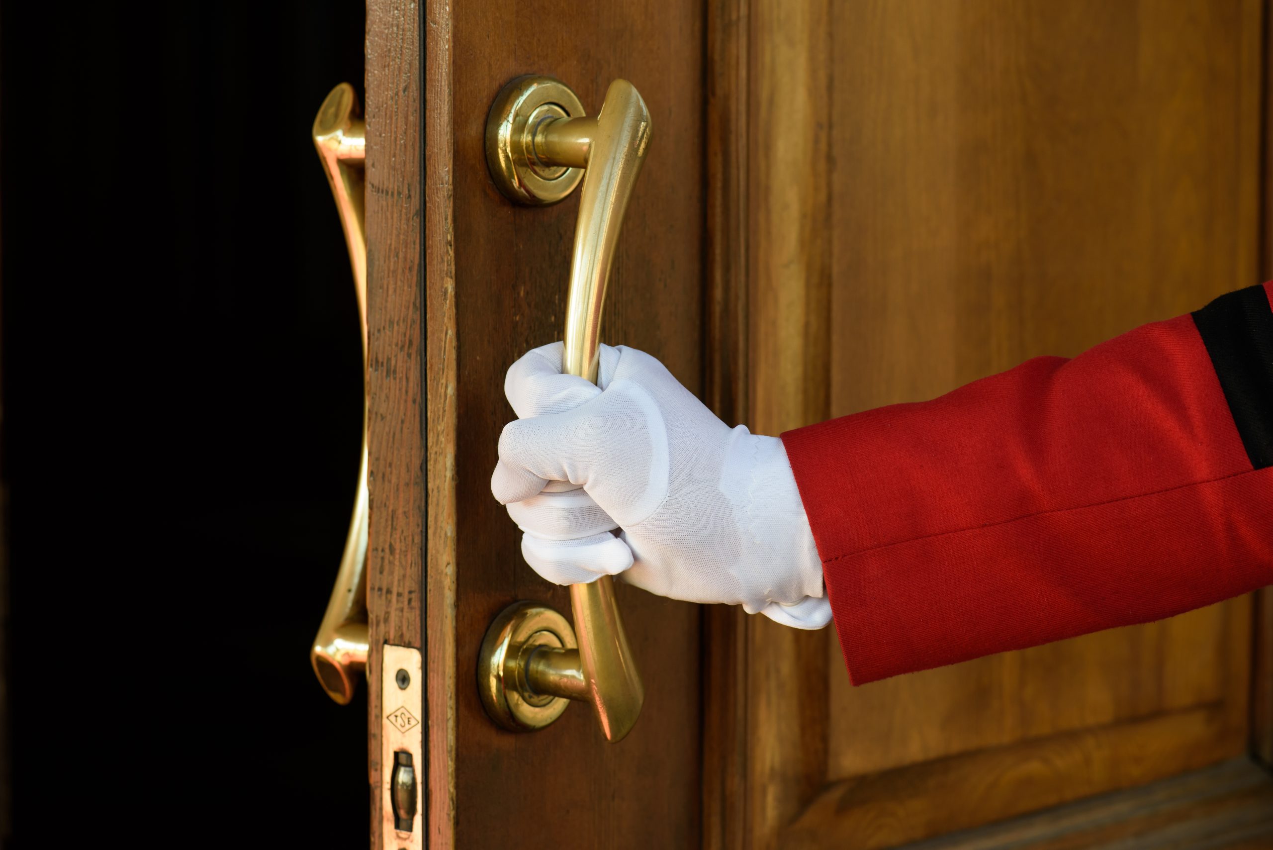 The Doorman Opens The Hotel Door Hands In White Gloves